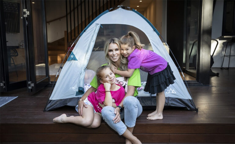 Mother and daughters smiling in front of a tent