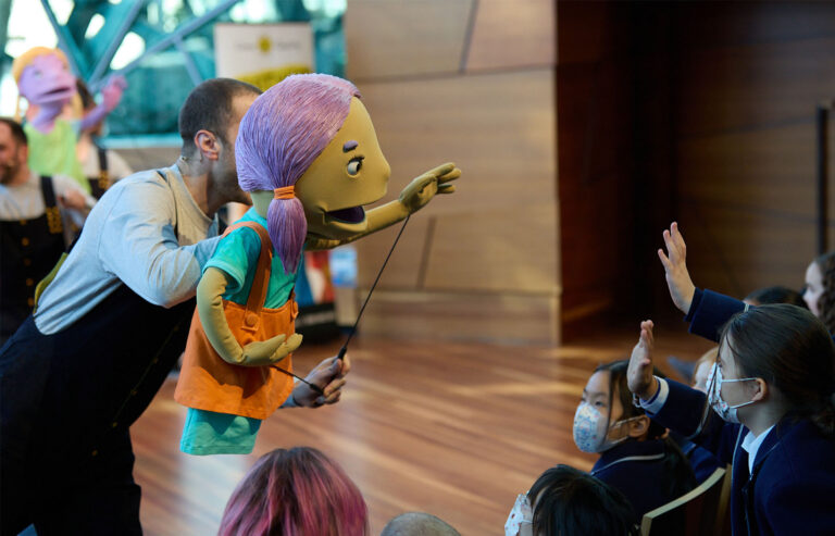 A puppeteer and Camp Quality Puppet perform to school children