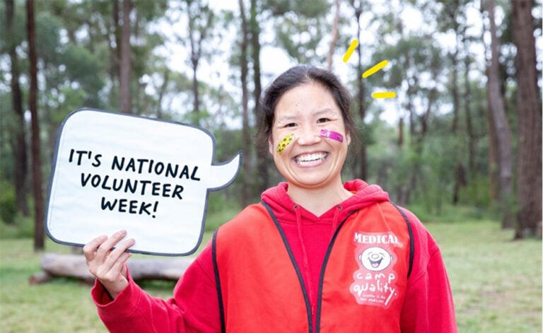 Dr Susan Yeung holding up a sign reading "It's National Volunteer Week"