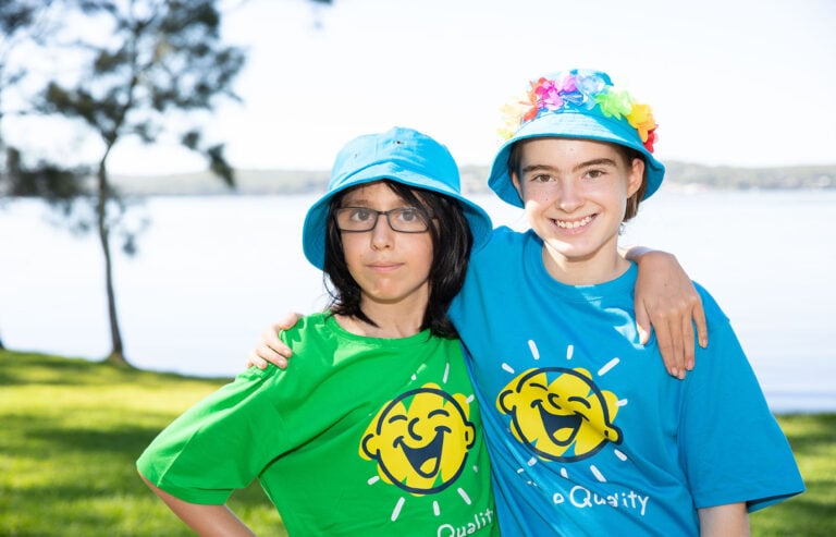Two kids at a Camp Quality camp with their arms around each others shoulders
