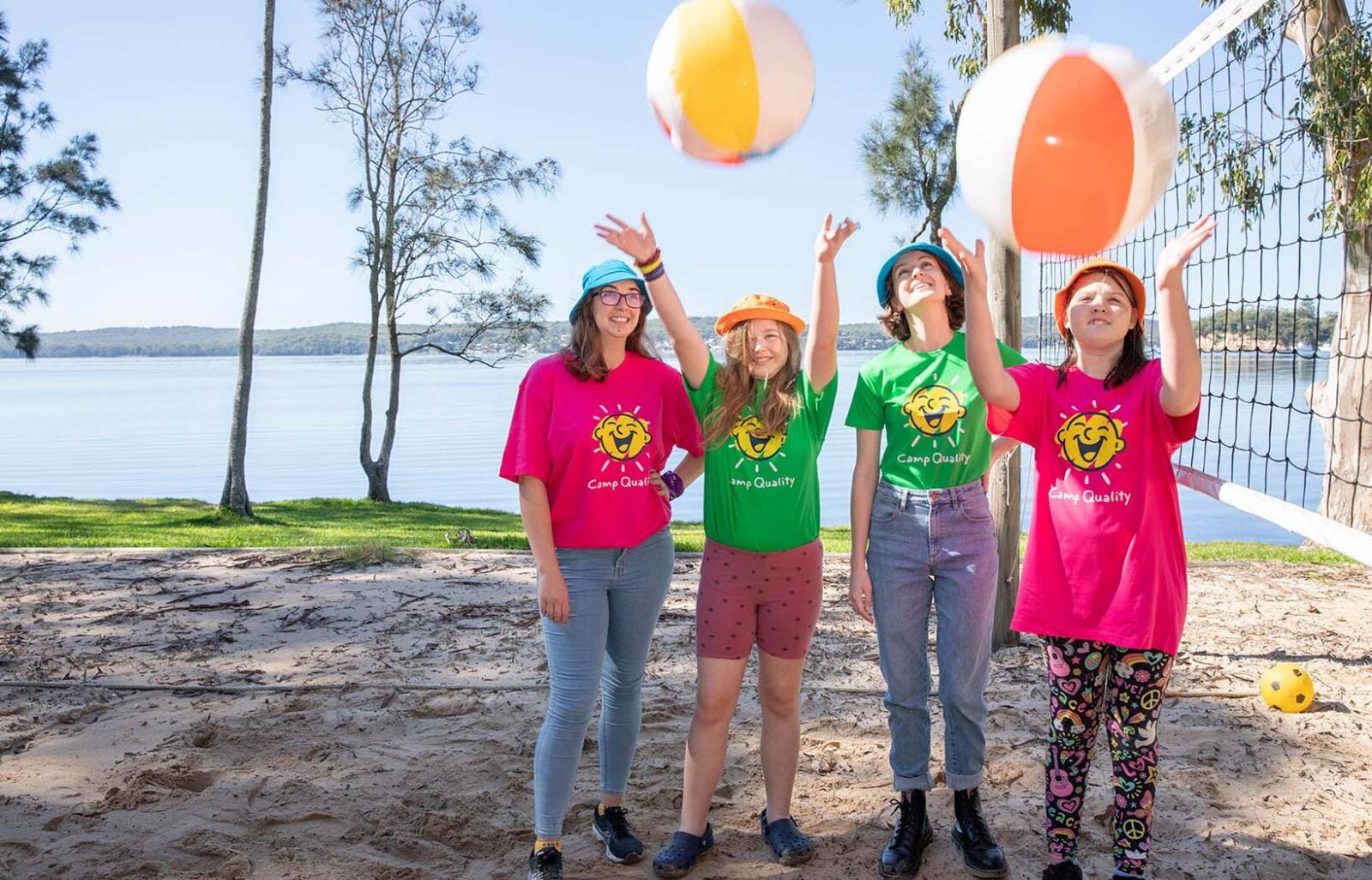 A group throws beach balls in the air at a Camp Quality camp