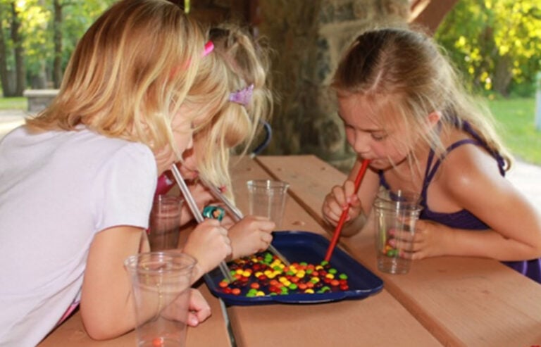 Kids playing a skittle race, blowing skittles with straws