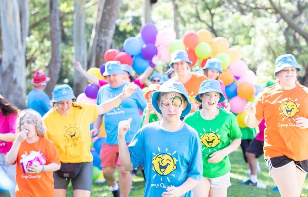Kids run excitedly at a Camp Quality camp