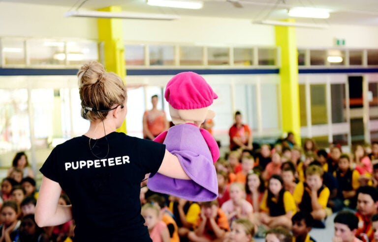 A Camp Quality puppeteer performs a puppet show at a school