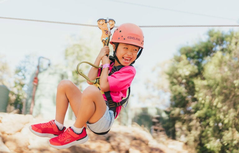 A girl rides on the flying fox at a Camp Quality Kids' Camp