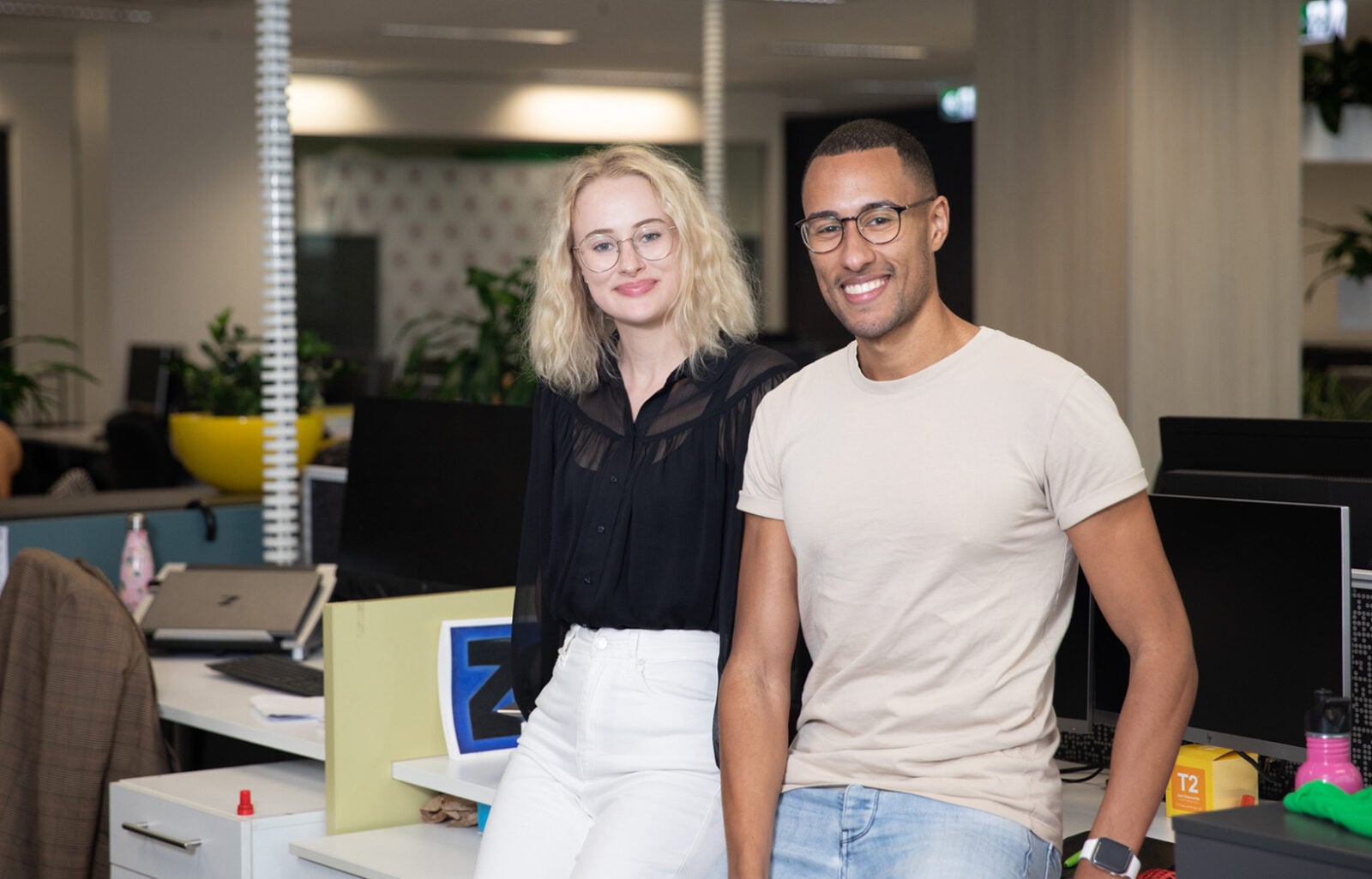 Two Camp Quality staff members lean against a desk in the Sydney office