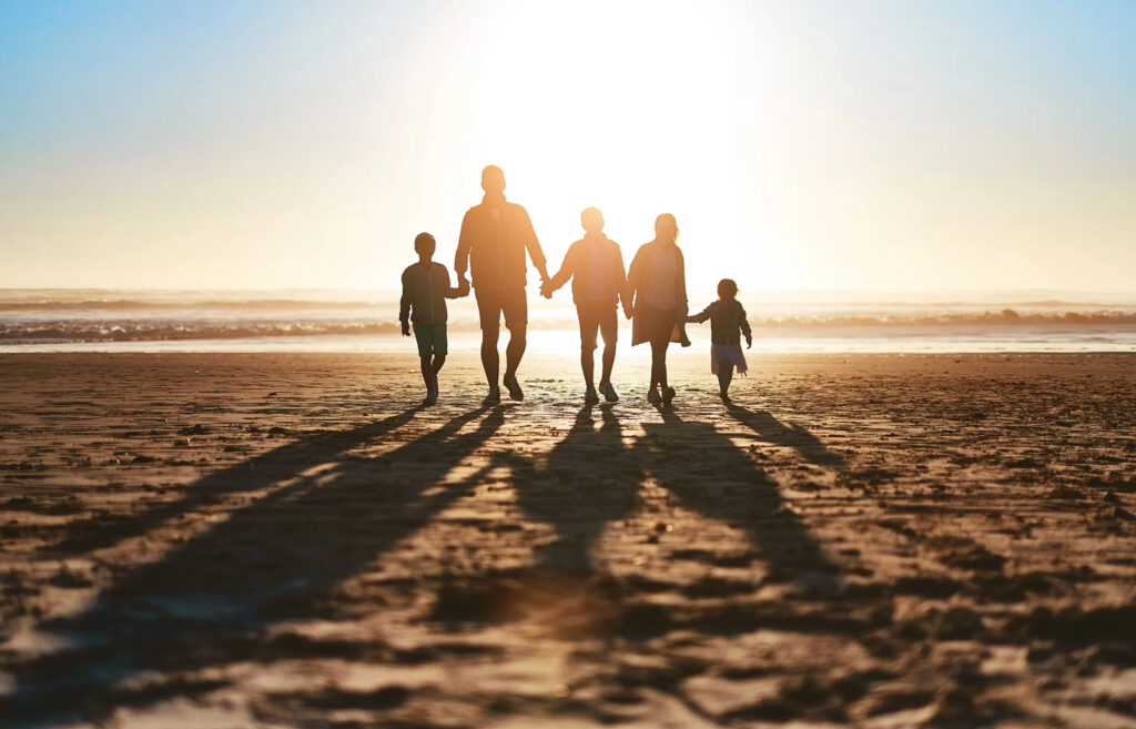 Silhouette of a family walking towards the sunset on the beach