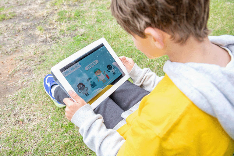 A young boy looks at the Kids' Guide to Cancer app on his tablet device