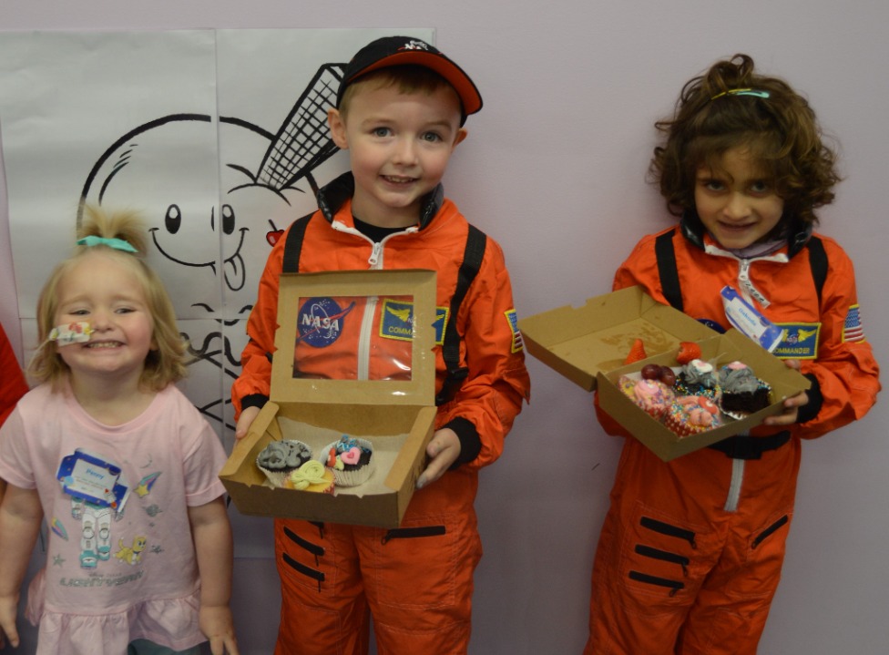Children dressed as astronauts holding cupcakes