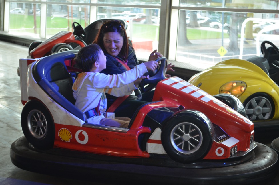 Mum and son smile at each other as they drive a dodgem car