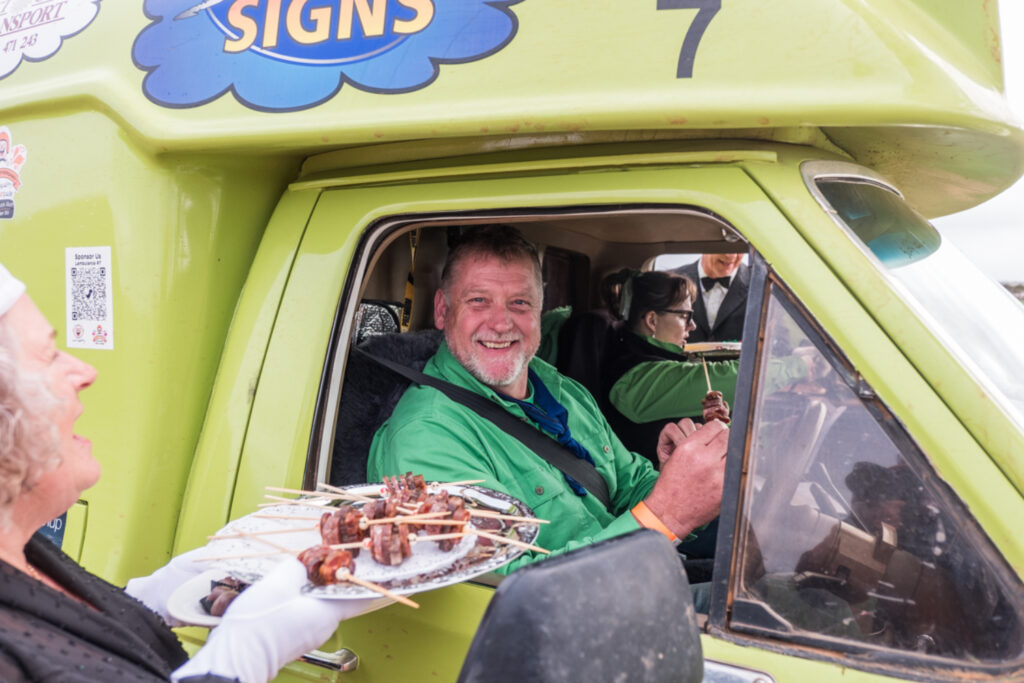 Man smiling in green truck while being served a kebab
