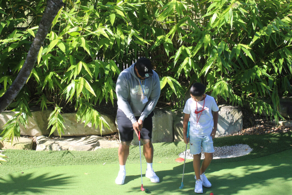 A dad and son play mini golf on a sunny day