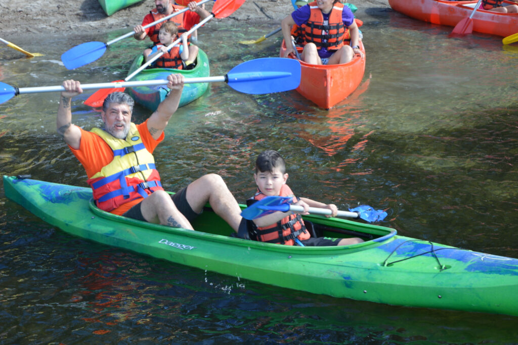Dad and boy smile in a Kayak