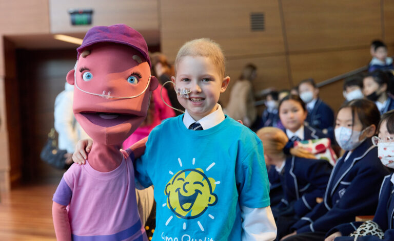 8 year old girl smiles with a Puppet. They both have nasal gastric tubes