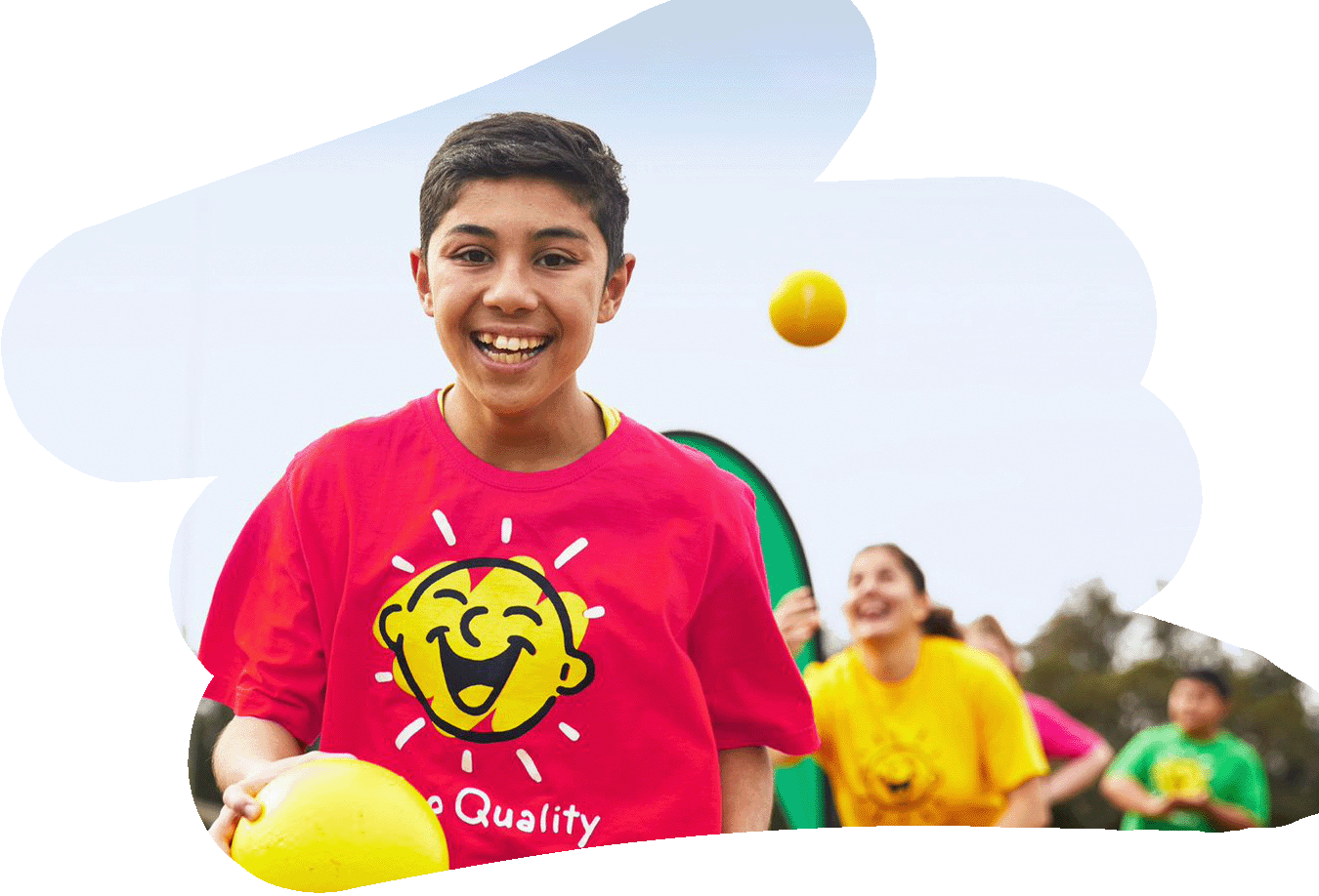 Child in pink Camp Quality shirt smiling while holding a yellow ball