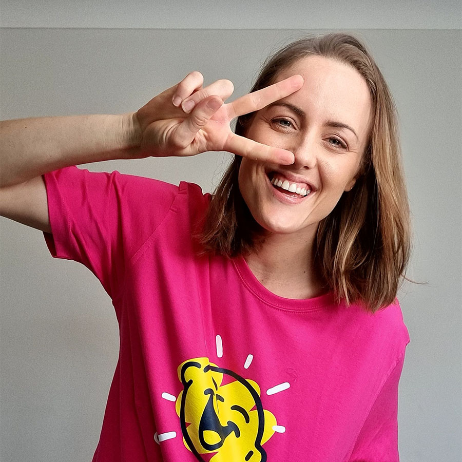 Ellie Cole smiling at the camera in a pink Camp Quality shirt