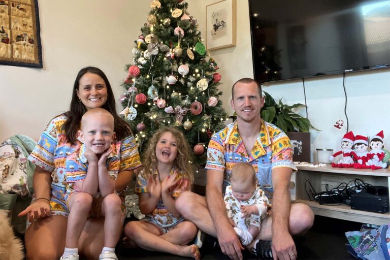 Theo and family sitting around Christmas Tree