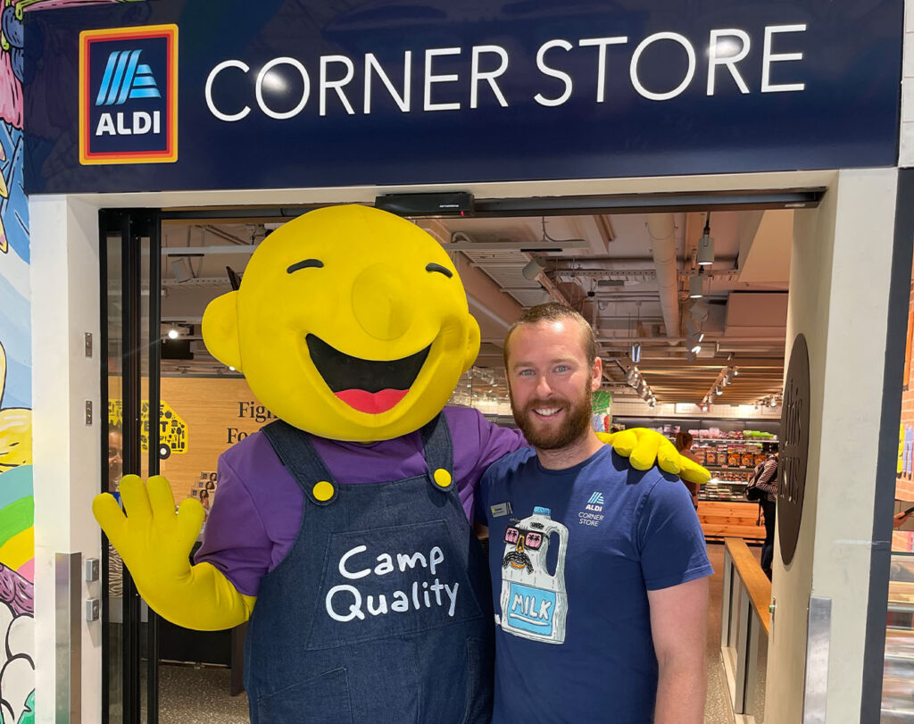 Camp Quality Giggle mascot posing with Aldi employee outside Aldi store