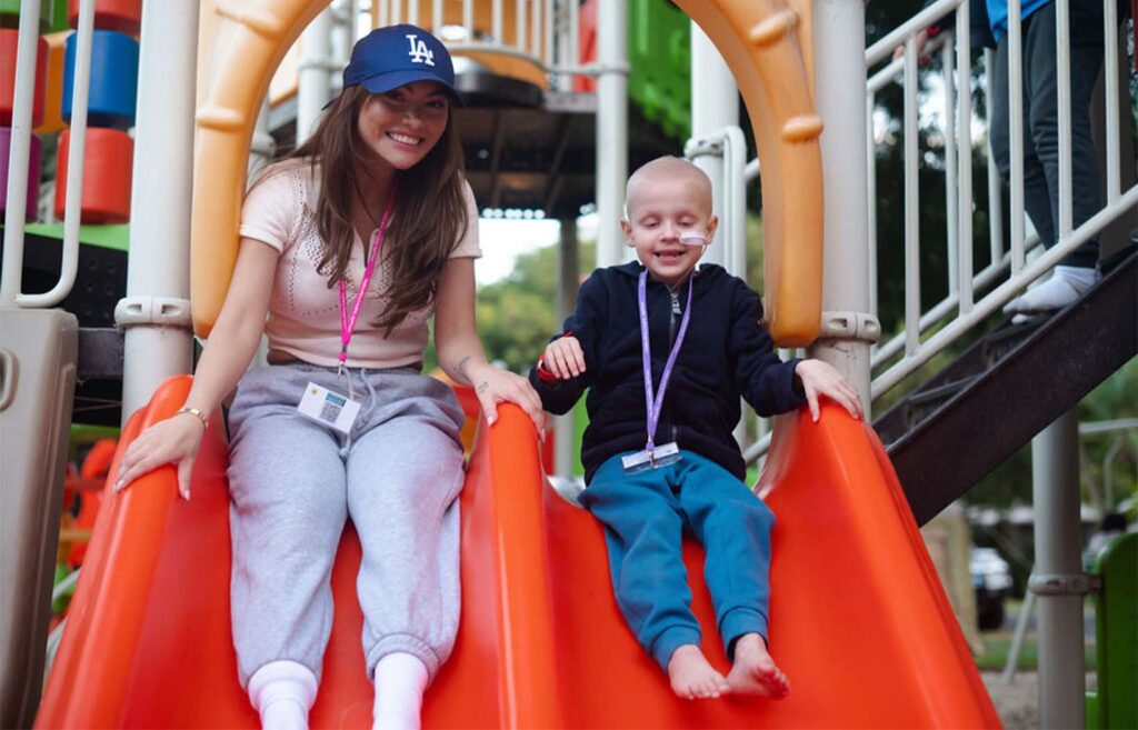 Camp Quality Volunteer with Camp Quality child on a slide