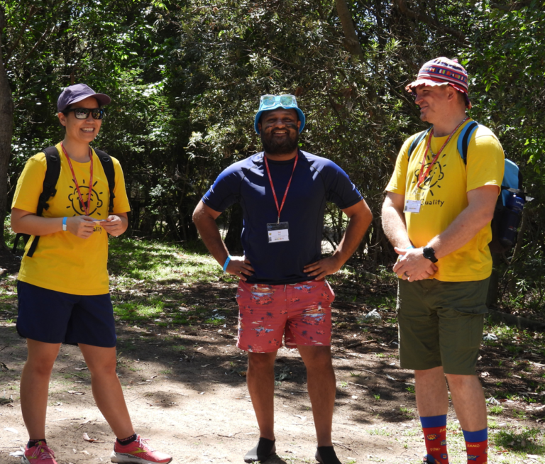 Image of Saj standing in between two other volunteers at a Family Camp.